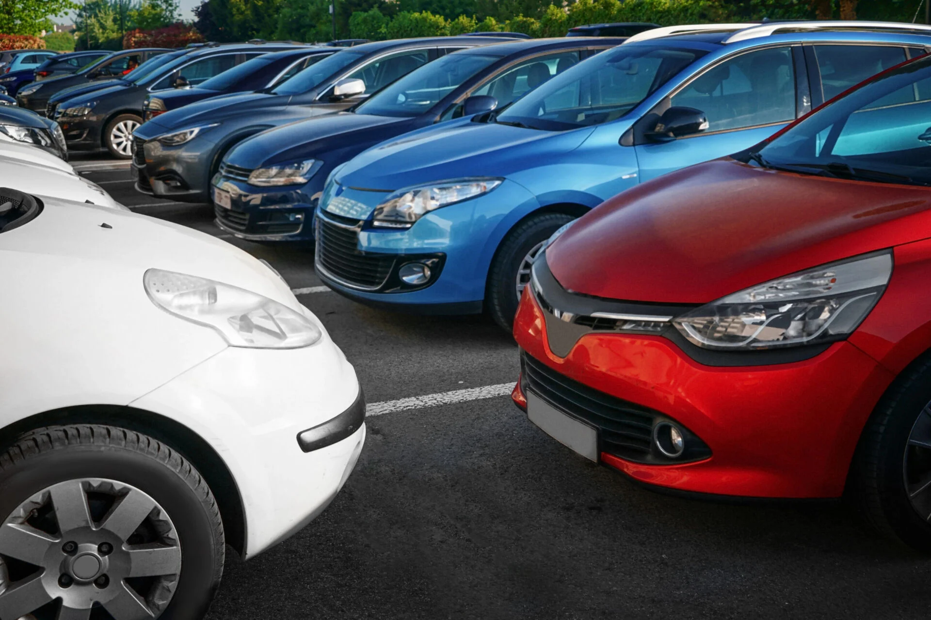 Row of modern cars in a parking lot on a sunny day.