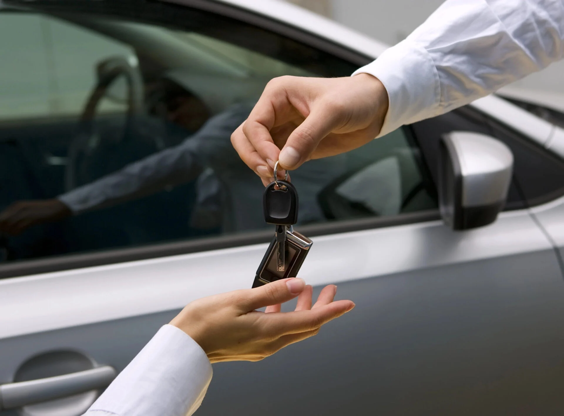 One person hands car keys to another