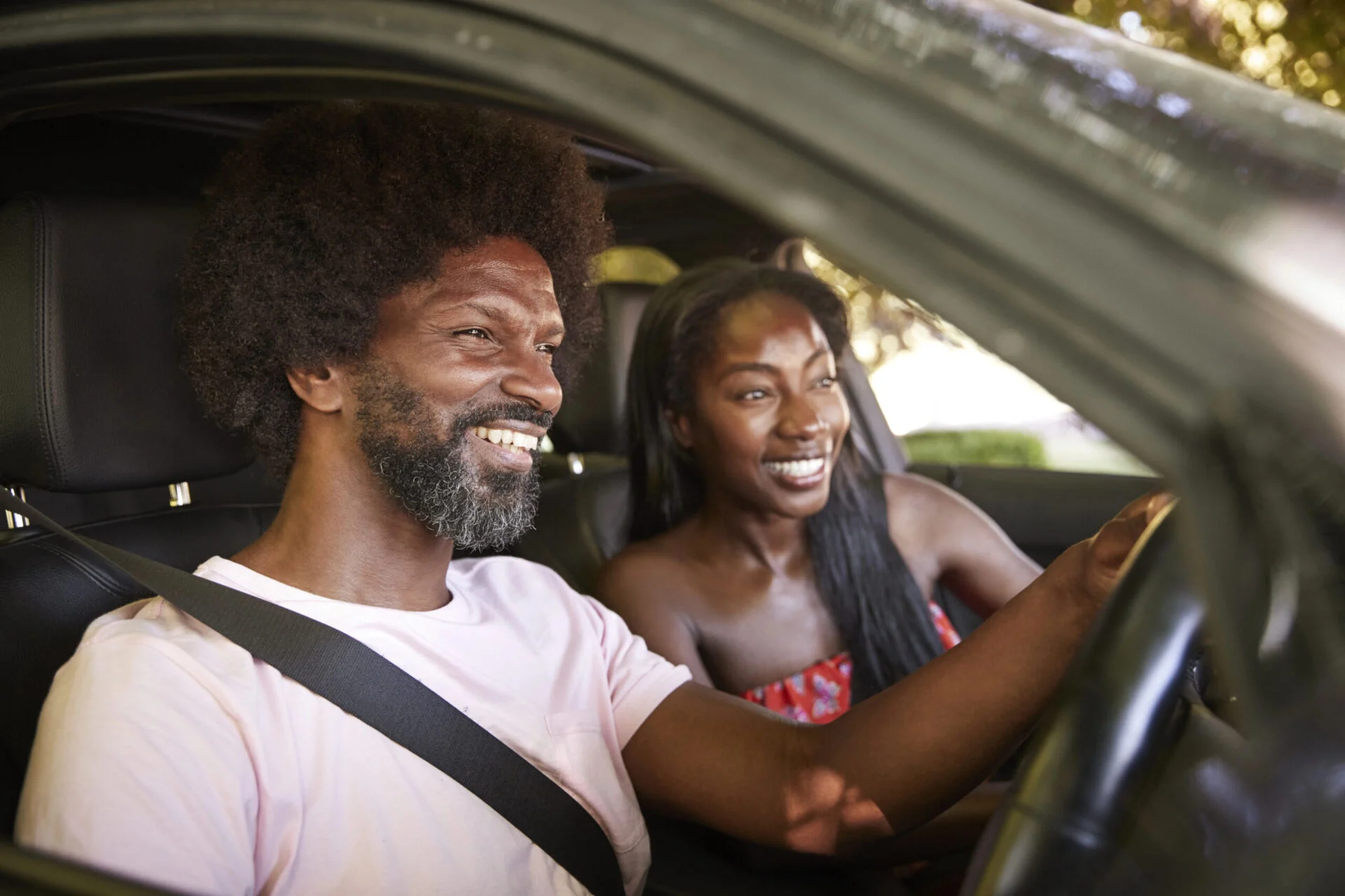 Man and woman drive in car while smiling