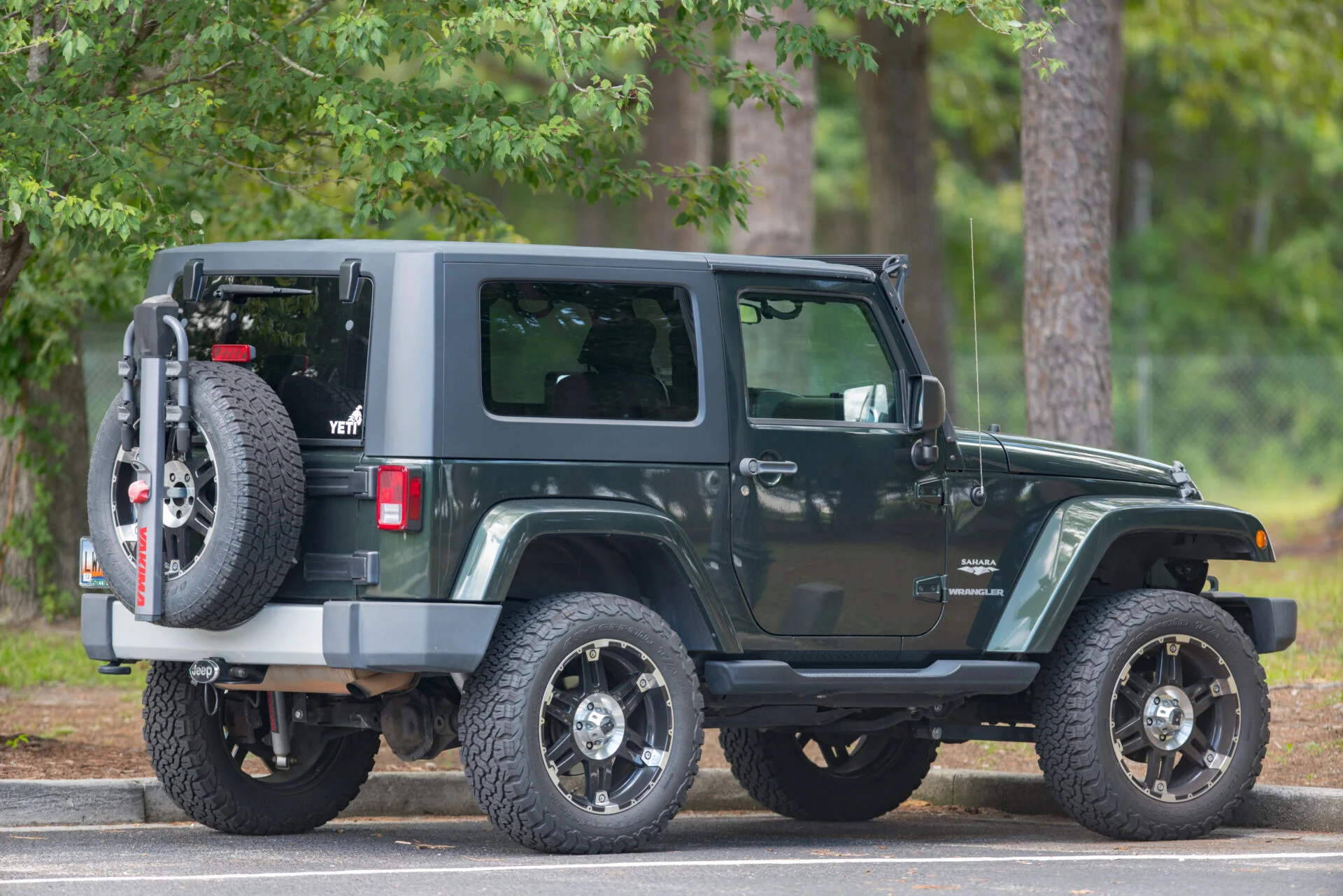 Side view of a jeep in a parking lot with trees all around