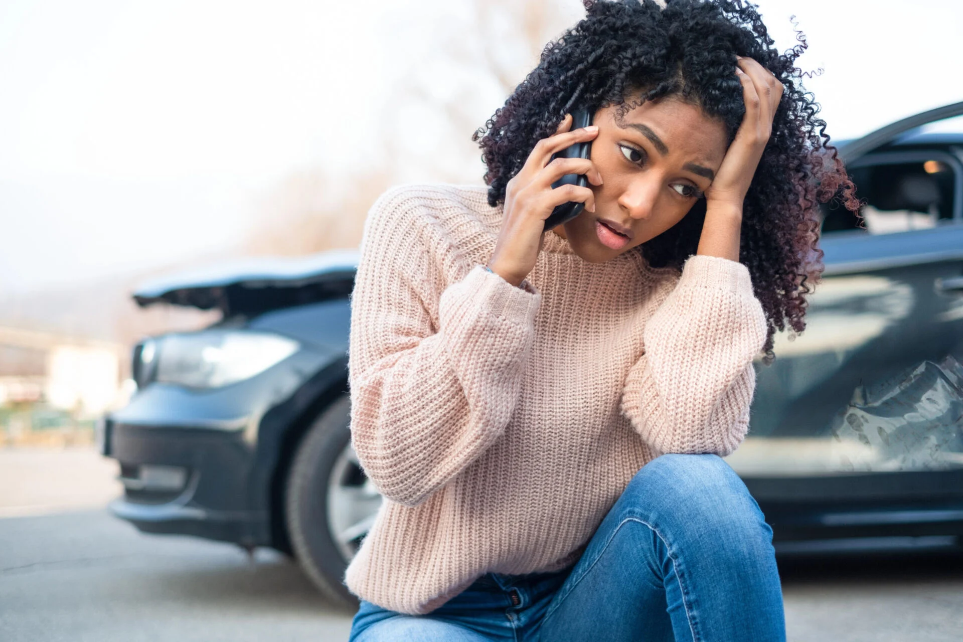 Woman on phone stressed in front of car accident