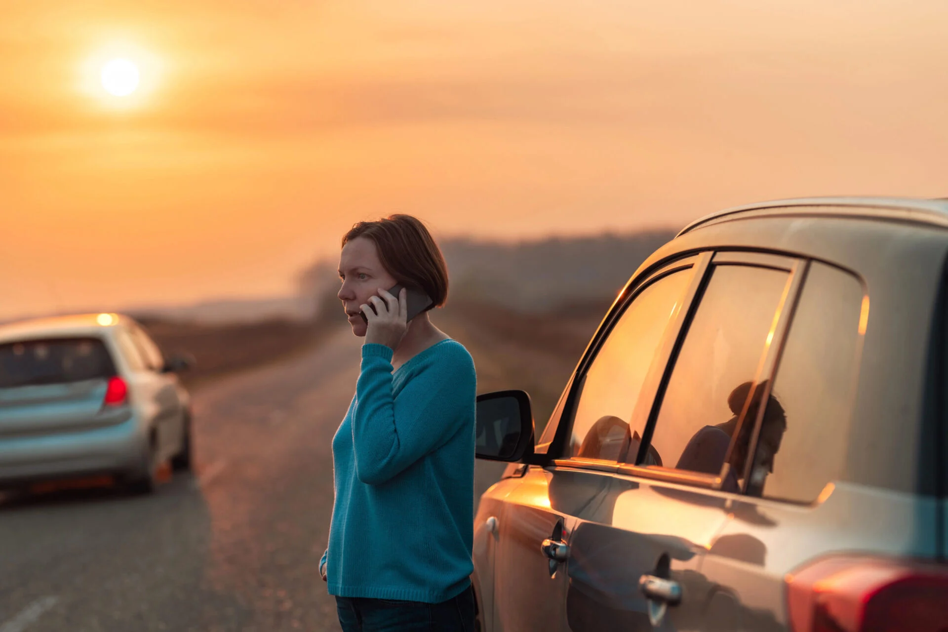 Woman on the phone with car on side of the road