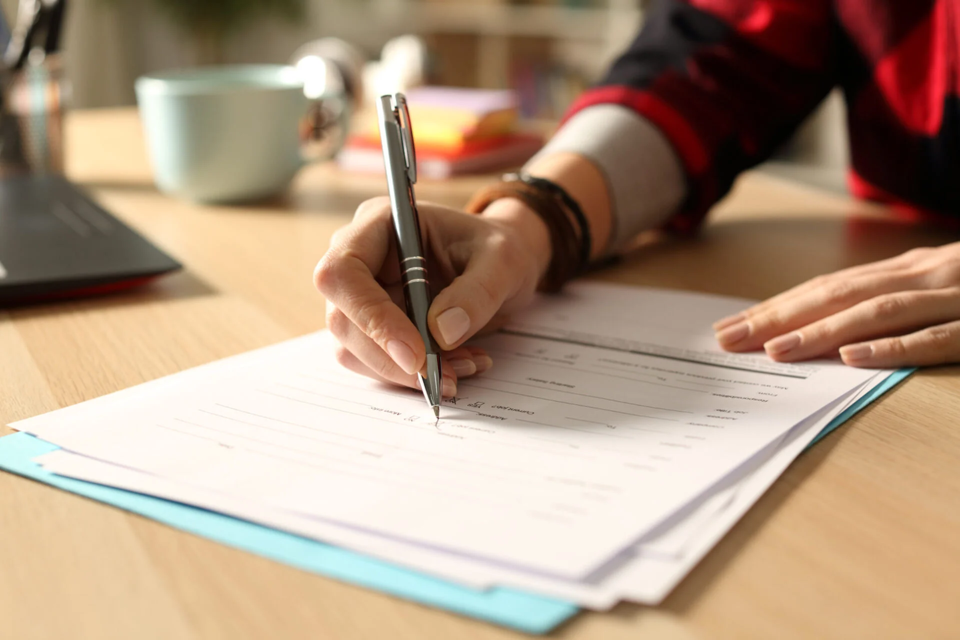 Close up of a person filling out paper work on a desk