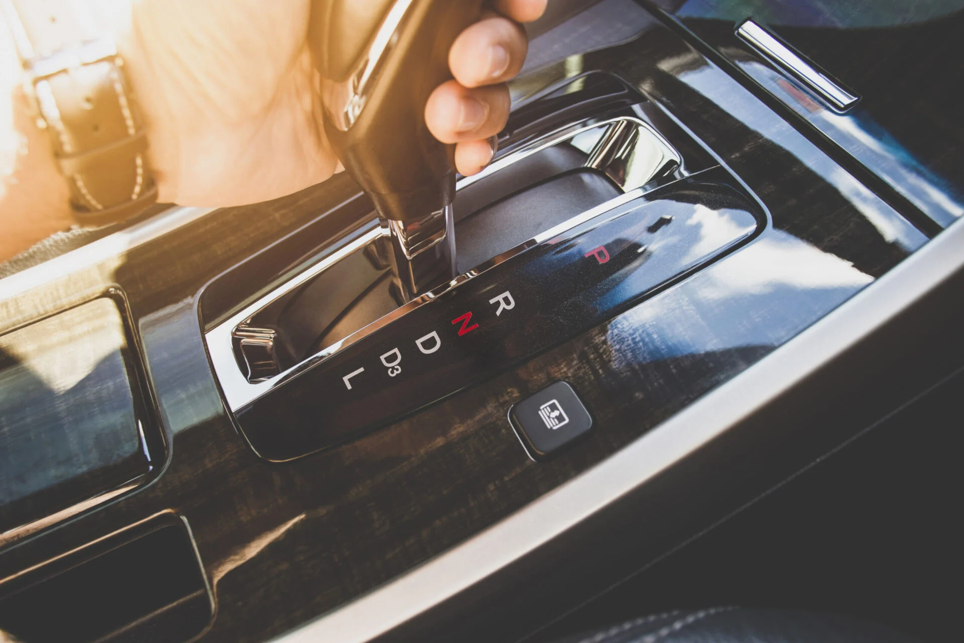 The driver's hand moved the gear selector to the neutral (N) mode of the automatic transmission in the car