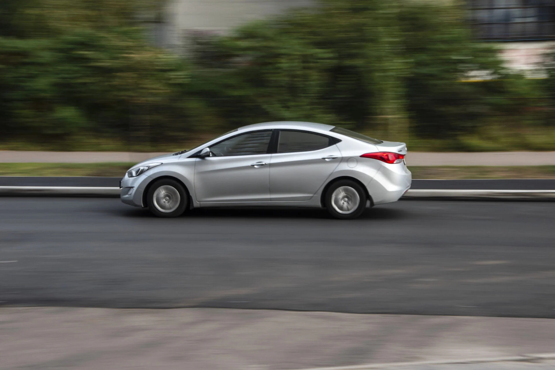 Sideview of of silver car driving on road.