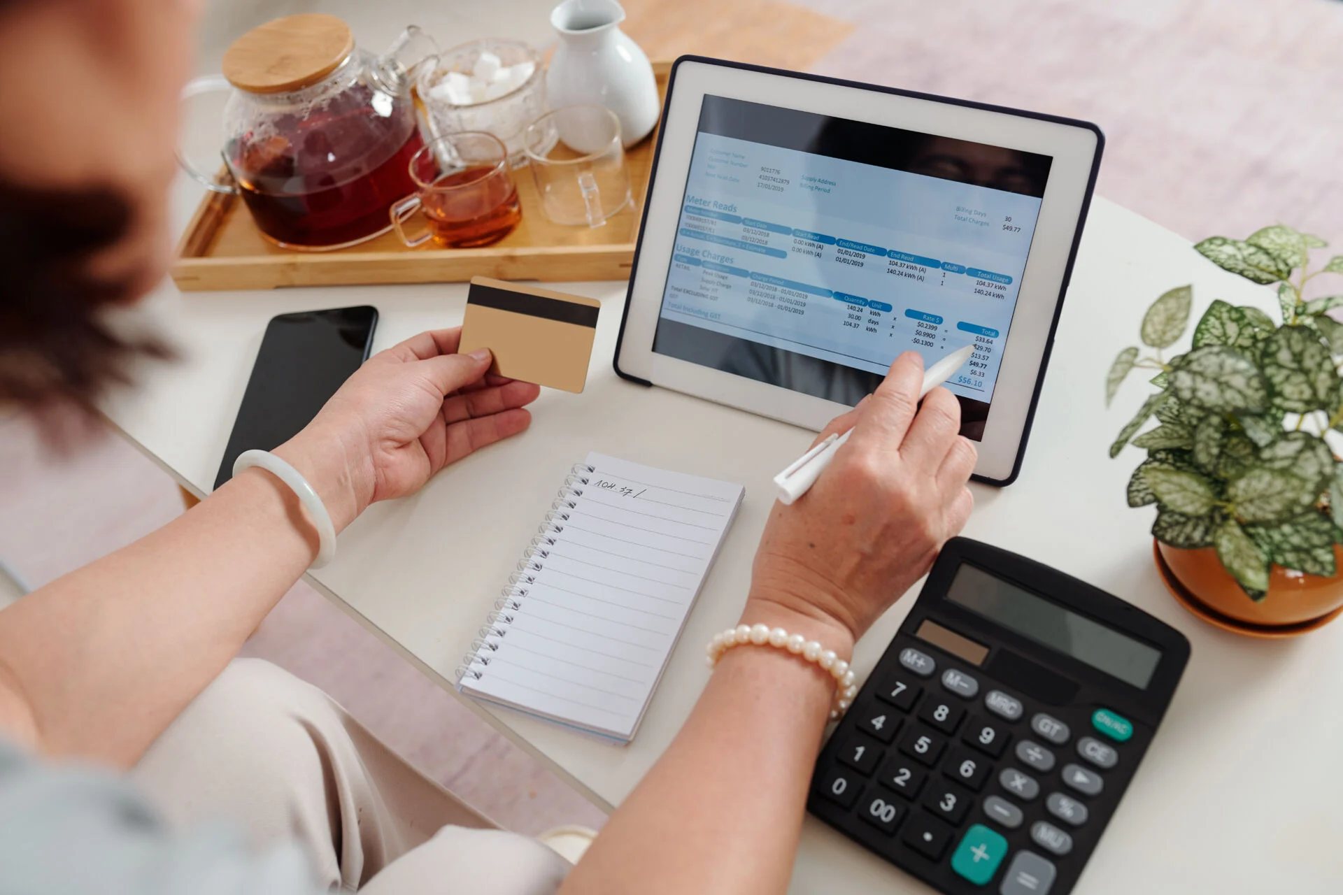 Hands of woman with credit card using application on tablet computer when paying bills