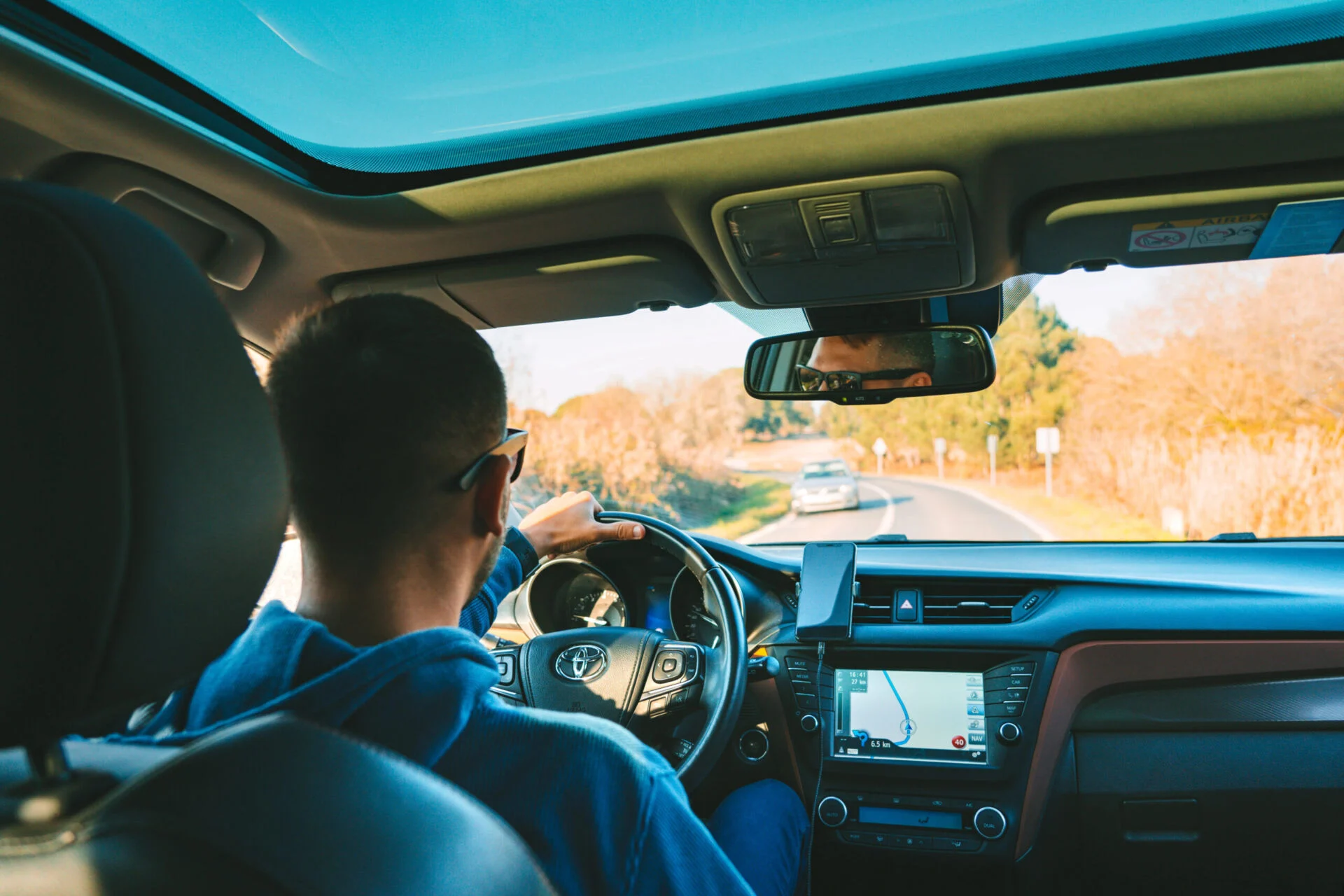 Person driving a Toyota car down a winding road