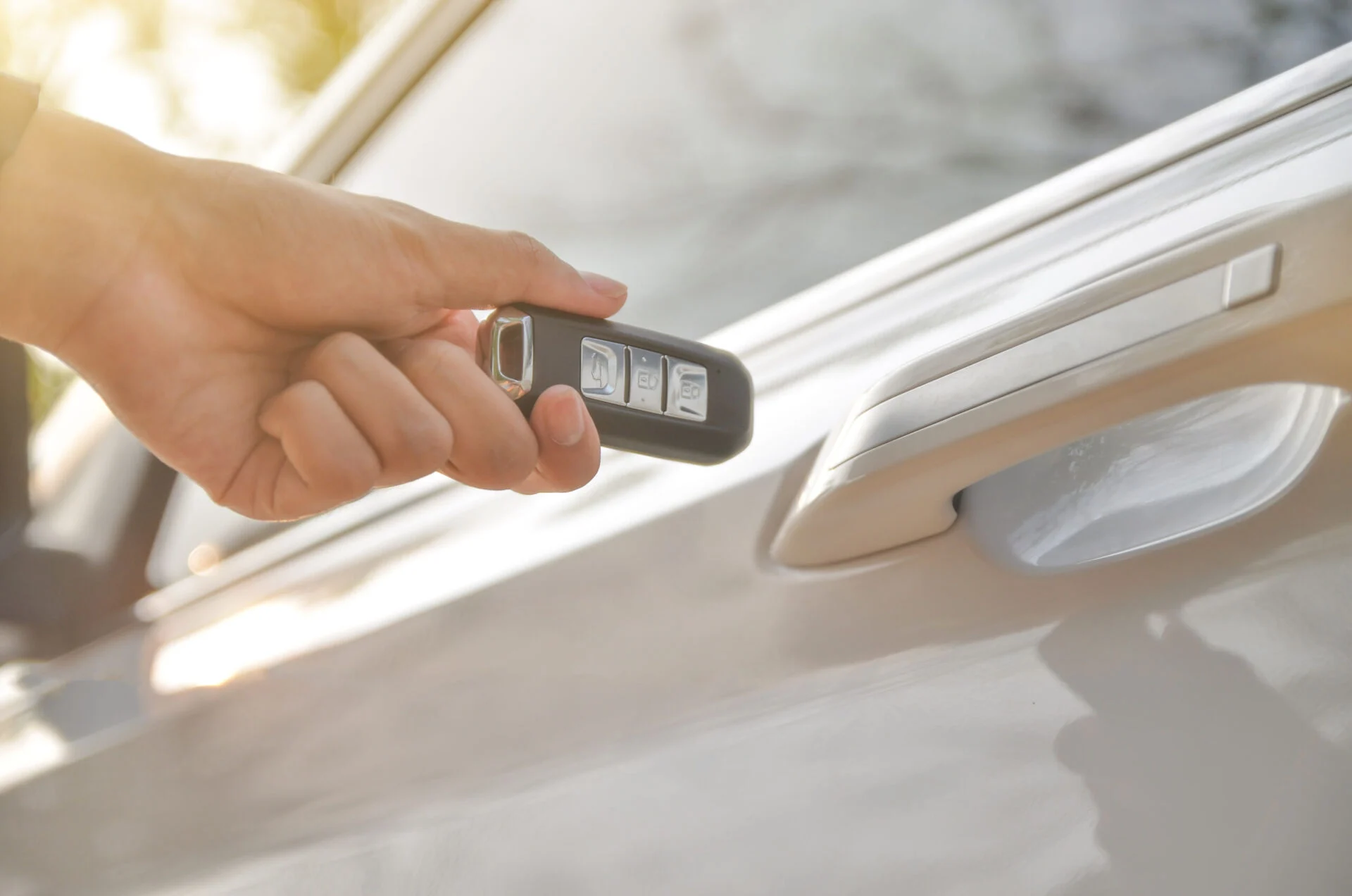 Person holding a key fob next to a vehicle door