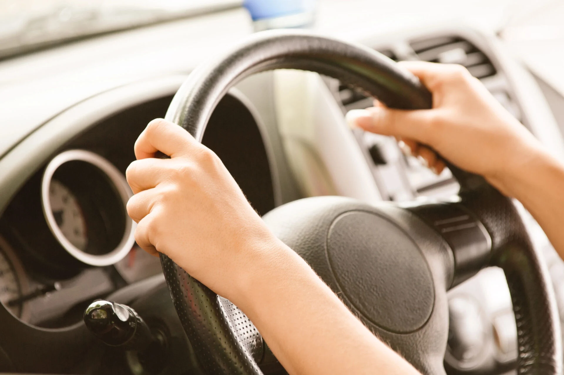 Person with both hands on a car steering wheel
