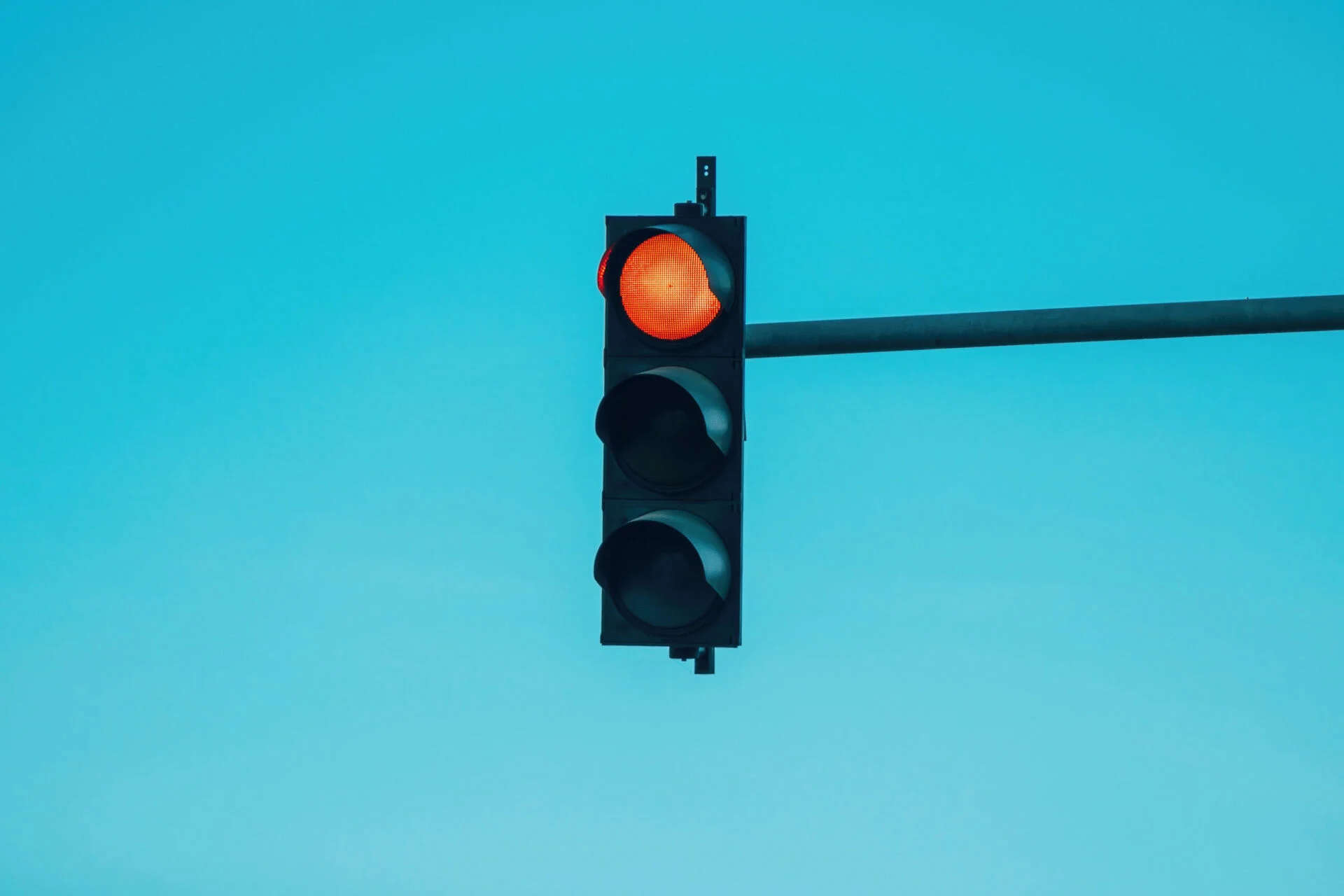 Red traffic light surrounded by blue sky