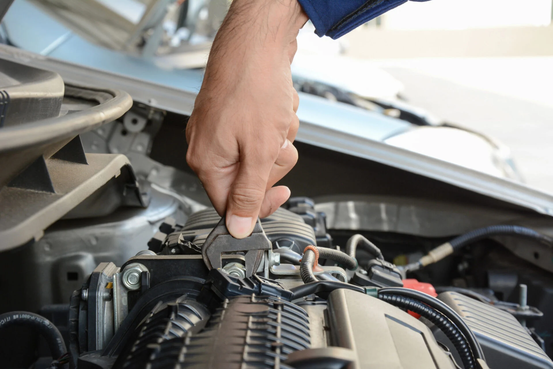 Person works on a car engine with a wrench